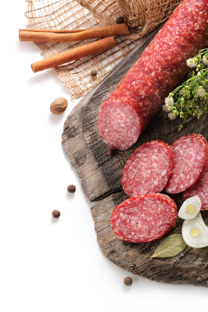 still-life with smoked sausage, salami bay leaf and onion on a wooden aged texture on a white backgroundの写真素材