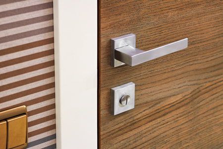 Modern metal door handle on wooden door textureの写真素材