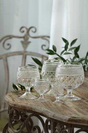 vintage glass goblets on a wrought-iron table with a wooden worktopの写真素材