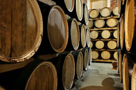 Rows of alcohol barrels in stock. Distillery. Cognac, whiskey, wine, brandy. Alcohol in barrels