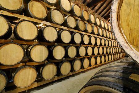 Rows of alcohol barrels in stock. Distillery. Cognac, whiskey, wine, brandy. Alcohol in barrels