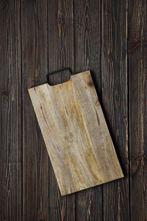 Wooden cutting board on a dark wooden background from boards. View from above. close-up. place for text. Food backgroundの写真素材