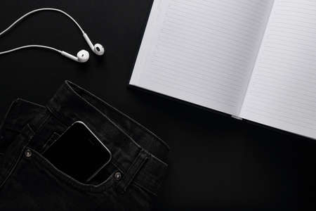 Headphones and a black phone in the pocket of jeans. BLACK ON BLACK PLACE FOR TEXTの写真素材