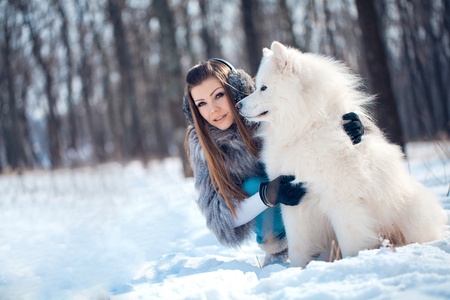 Happy woman with Samoyed dog in winter forestの写真素材