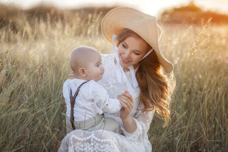 Beautiful pretty woman with baby boy on sunset outdoors. mother with sonの写真素材