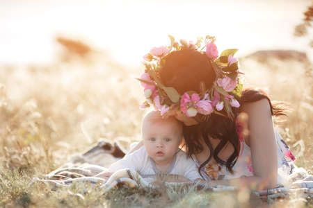 mother feeding her newborn baby boy from bottle outdoors in the field. artifitial milk feedngの写真素材