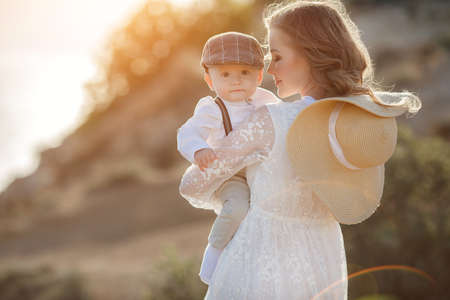 Beautiful pretty woman with baby boy on sunset outdoors. mother with sonの写真素材