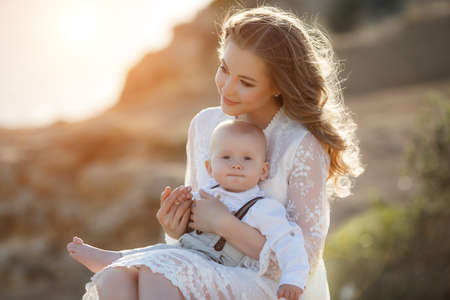 Beautiful pretty woman with baby boy on sunset outdoors. mother with sonの写真素材