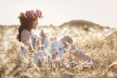 mother feeding her newborn baby boy from bottle outdoors in the field. artifitial milk feedngの写真素材