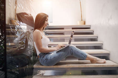 Pretty young woman working at home with laptopの写真素材