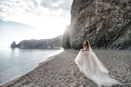 bride by sea. waves and mountains background. wedding on shoreの写真素材