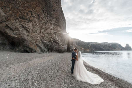 Wedding couple in a beautiful place by sea and mountains, Bride and groom on beachの写真素材