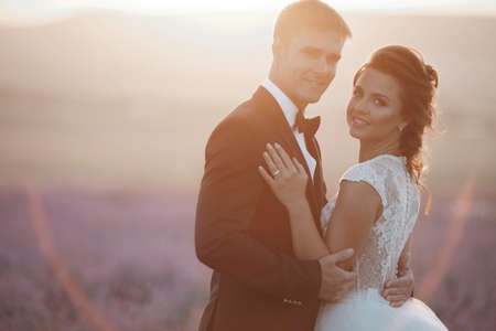 Wedding couple in a lavender field at sunset, bride and groomの写真素材