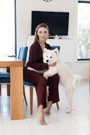 Young smiling woman with dog at home indoorの写真素材