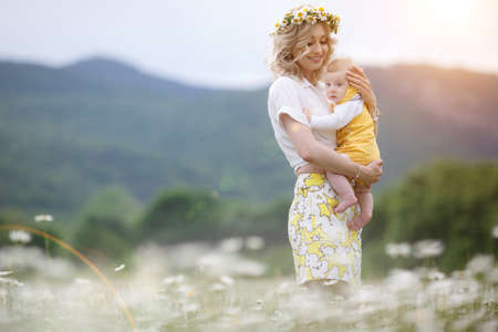 happy woman with little baby boy in camomilles. blooming white field. family in flowers. mother and sonの写真素材