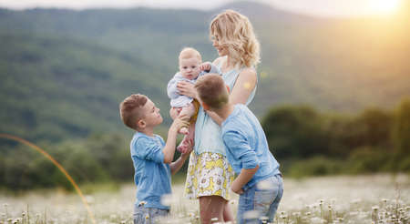 happy family in camomile field. woman with three children boys in camomiles outdoorsの写真素材