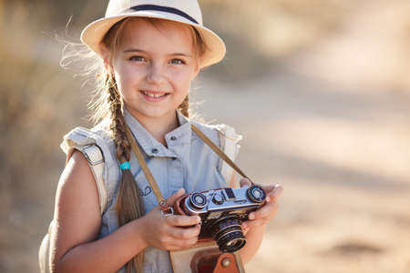 child girl traveler. trip alone. girl walking with camera and suitcase on nature by sea. travel, vacation, holidaysの写真素材