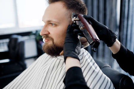 Portrait of a man in Barbershop, shave and cut by barber girl