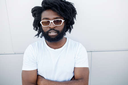 Portrait of a black handsome man outdoor near white backgroundの写真素材