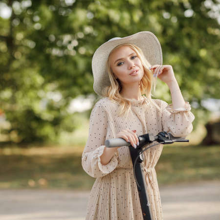 Young woman with elecritc scooter in sunsetの写真素材