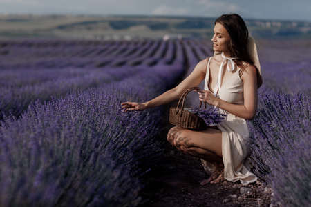 Young beautiful woman sitting in lavender fieldの写真素材