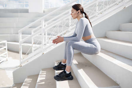 portrait of fitness woman outdoor sitting on stairs at stadium
