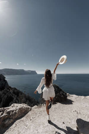 back side fashion young woman in dress with hat outdoor near the sea oceanの写真素材