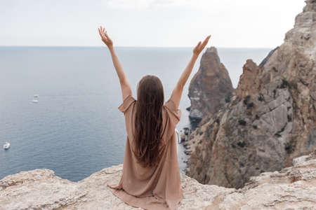 pretty woman on the edge on mountain on sea and sky background. summer nature. beauty portraitの写真素材