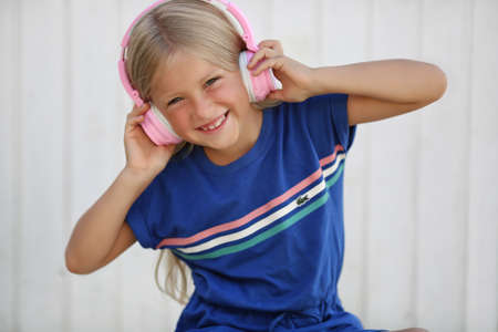 pretty preteen girl having fun outdoors with headphones in summer warm day.