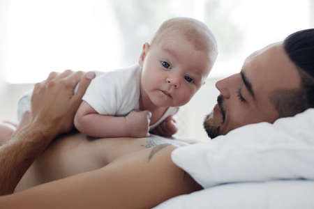 man with infant. happy family at home. happy father with cute two months baby boy laying in light...