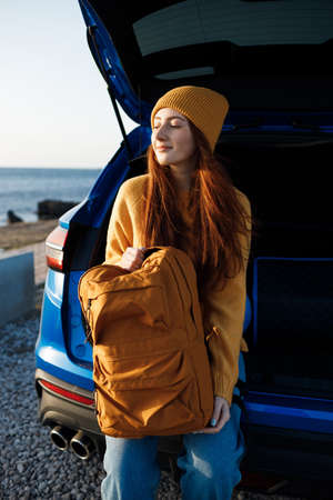 cute casual woman with red hair ready for travel by car