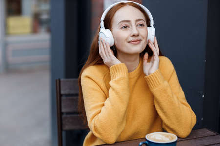 cute woman with headphones in cafe outdoorの写真素材