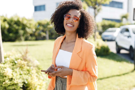 smiling Afro American woman with phone outdoorsの写真素材