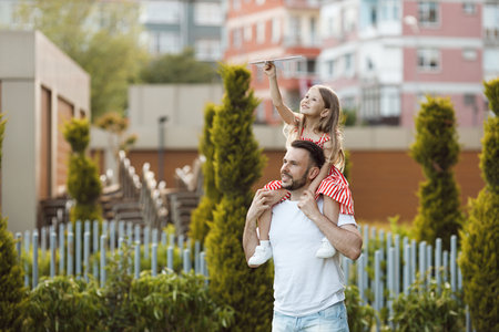 happy father and daughter with paper airplane outdoorの写真素材