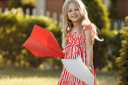 little cute girl with paper airplane outdoorの写真素材