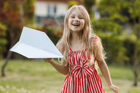 little cute girl with paper airplane outdoorの写真素材