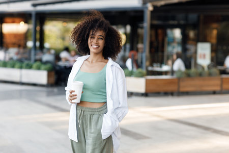 pretty young afro woman with coffee outdoorsの写真素材