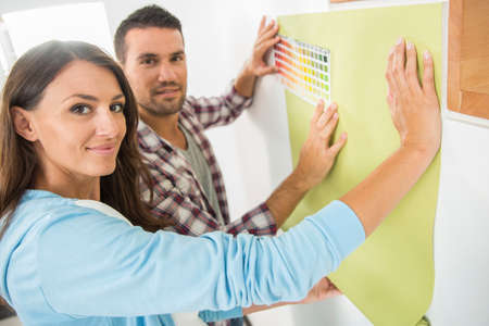 Young couple choosing paint color and pent paperの写真素材