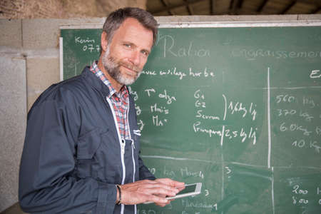 farmer using a digital tablet in a barnの写真素材