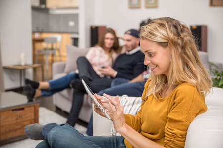 young woman sitting in sofa with tabletの写真素材