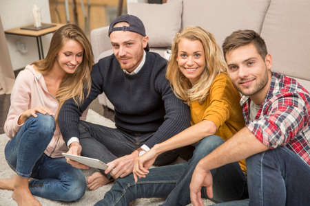group of friends looking at pictures on tablet
