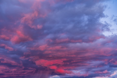storm clouds over the city during sunset. The sky has a purple color due to the effect of the sun.の写真素材
