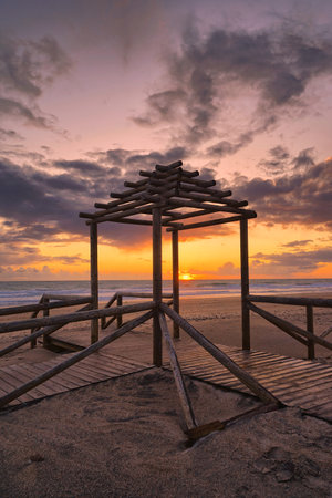 Stunning sunset over Cadiz beach, with golden hues reflecting on the Atlantic, framed by serene sands and historic skyline.の写真素材