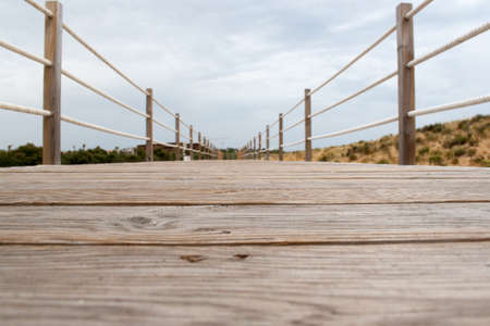 wooden bridge with rope handrail in perspectiveの写真素材