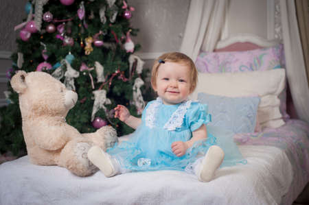 Little princess wearing a blue dress sitting on a bedの写真素材