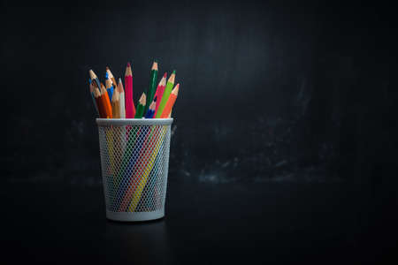 glass with colored pencils on black background blackboard chalk for drawingの写真素材