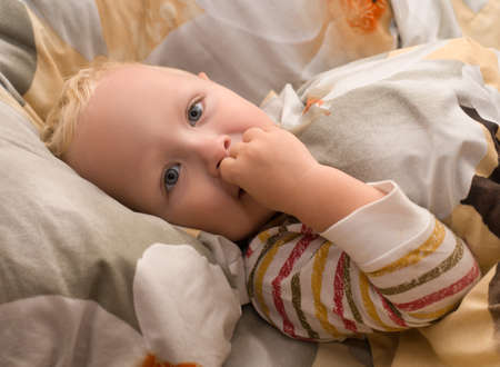 Smiling, happy baby lying in bed does not want to sleepの写真素材