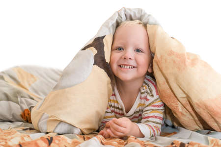 Smiling, happy baby lying in bed does not want to sleepの写真素材