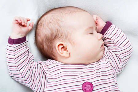 Portrait of a beautiful baby girl sleeping on white blanket.の写真素材
