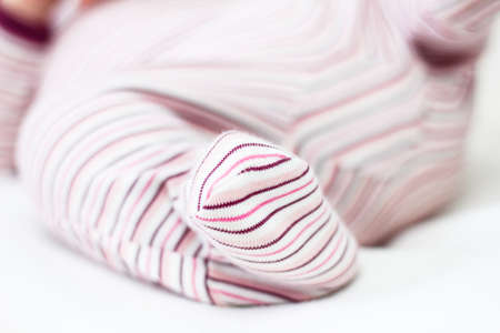Newborn baby in pajamas, leg close-up. Infant lying on his back. Baby sleepers.の写真素材